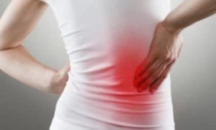 Person holding lower back in pain with a red-highlighted area, indicating discomfort or injury.